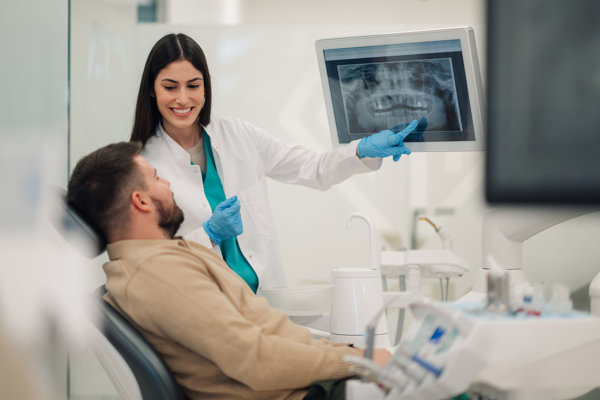 Dentist showing teeth x-ray to patient in modern clinic