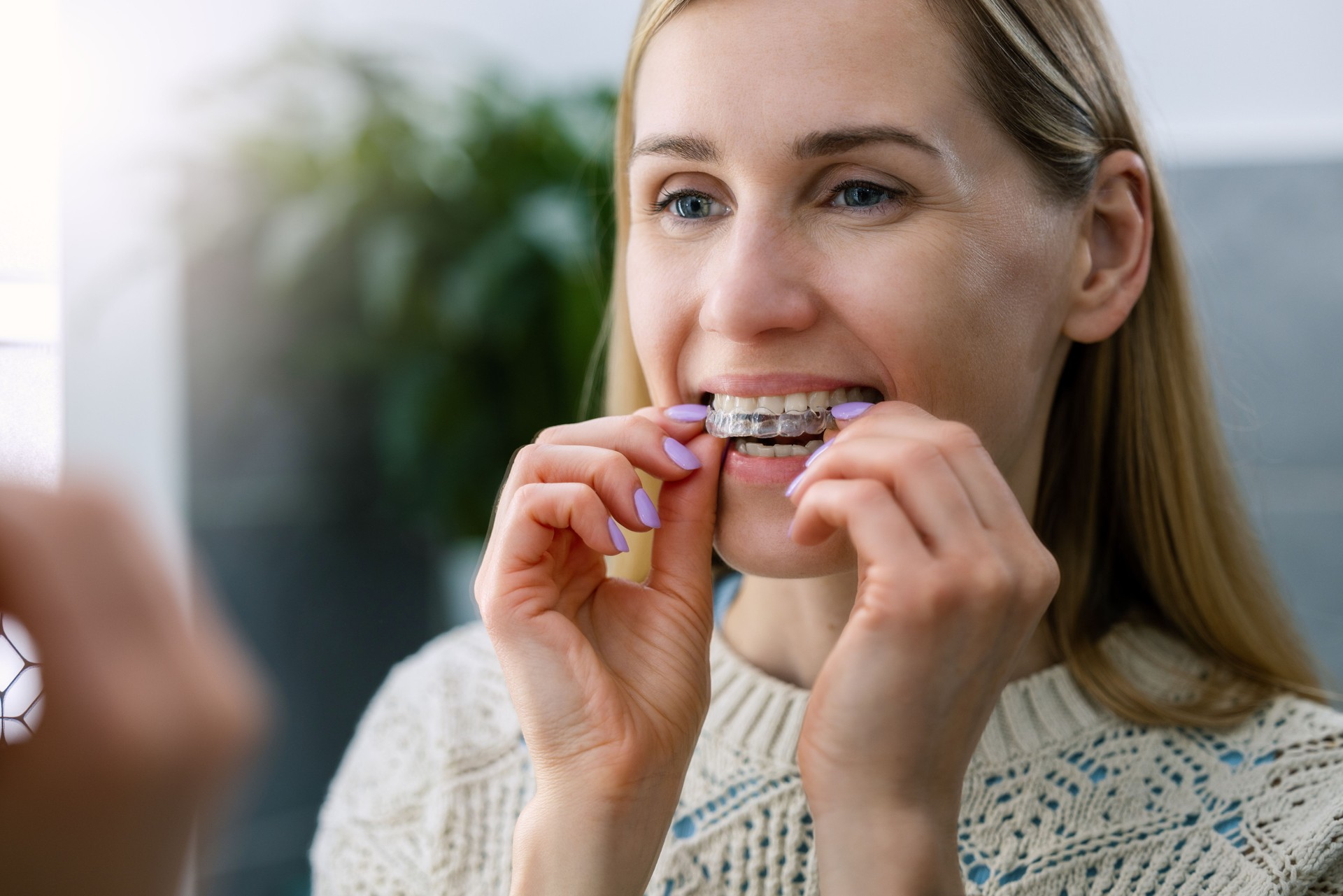 woman inserting transparent invisible dental aligners for crooked teeth straightening